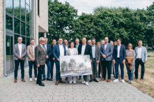 Gruppenfoto nach der Vertragsunterzeichnung: Vertreterinnen und Vertreter aus Politik, Verwaltung und dem Unternehmen GOLDBECK präsentieren gemeinsam mit Landrat Frank Rock und Schulleiterin Anna Emmans die Planungen für den neuen Bauabschnitt am Berufskolleg Bergheim.